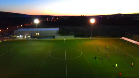 Revealing-shot-of-a-football-field-at-dusk-where-people-are-playing-under-lights-at-Santa-Ponsa,-Mallorca,-Spain