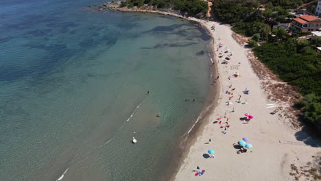 Langer-Weißer-Sandstrand-Mit-Touristen-Unter-Bunten-Sonnenschirmen,-Die-Sommerferien-Auf-Sardinien,-Italien,-Erleben