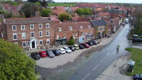 Still-Aerial-Drone-Shot-of-Old-Small-Village-Burnham-Market-with-Cars-and-Cyclists-Passing-by-in-North-Norfolk-UK-East-Coast