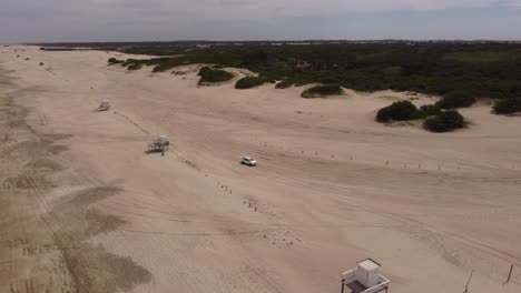Aerial:-4-Wheel-Vehicles-driving-and-leaving-Sandy-Beach-during-sunny-day---Mar-de-las-Pampas,Argentina