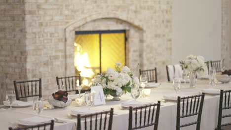 Interior-wedding-venue-dining-tables-prepared-for-guests-by-cozy-fireplace