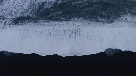 Fierce-waves-of-the-Atlantic-hitting-black-sand-beach-in-Iceland---aerial-straight-down