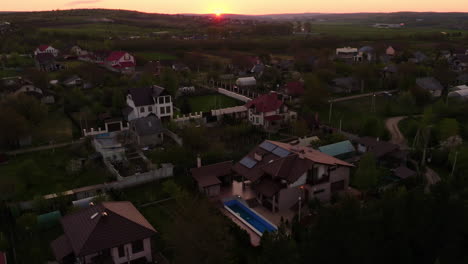 Landscape-aerial-drone-shot-of-a-luxury-modern-house,-surrounded-by-forests,-in-a-village-in-Moldova,-at-sunset