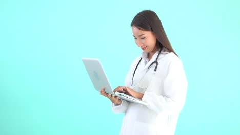 A-young-female-healthcare-professional-holds-a-laptop-in-one-hand-and-enters-data-with-other,-copy-space