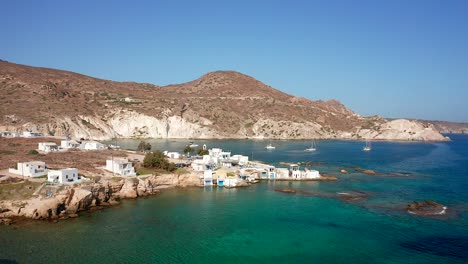 Dolly-in-of-Mandrakia-bay,-houses-and-boats-in-Mediterranean-sea-at-milos-isalnd