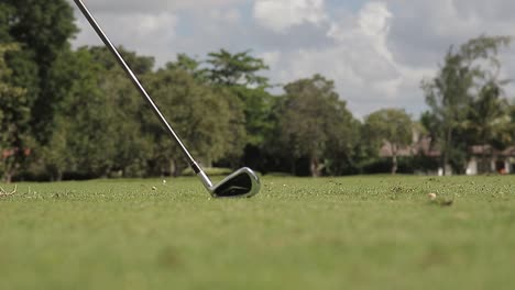 Low-angle-close-up-shot-at-the-golf-club,-hitting-a-golf-ball-across-a-golf-course,-slow-motion