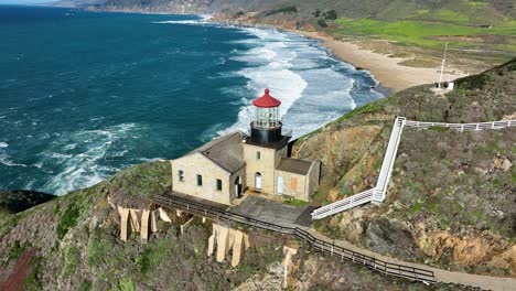 Aerial-shot-of-Point-Sur-Lighthouse-on-Sea-cliff-against-blue-ocean-waves,-Big-Sur-California