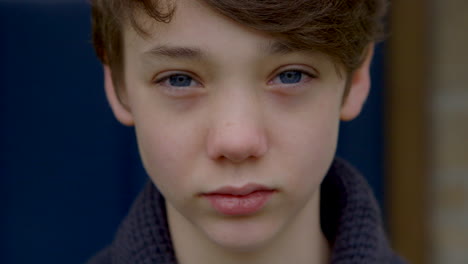 Attractive-sad-boy-with-blue-eyes-looks-into-camera,-closeup