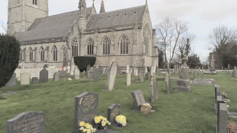 Rural-Welsh-cemetery-garden-graveyard-headstones-in-front-of-ornate-white-church-slow-dolly-right