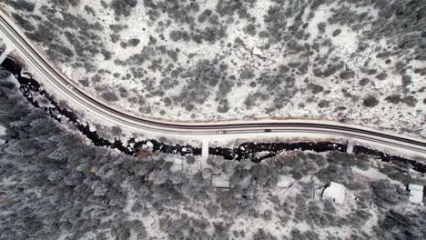 Drone-Aerial-View-Of-Cars-Driving-On-Isolated-Road-In-Snow-Covered-Winterscape-Pine-Tree-Woodland-Hills-Valley-Near-Kittredge-Evergreen-Colorado