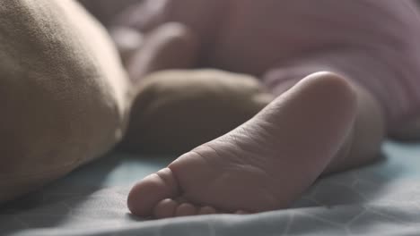 Handheld-close-up-of-baby-girl-foot-while-sleeping-on-bed-at-home