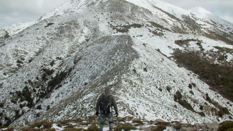 Rückansicht-Eines-Bergsteigers-Auf-Dem-Schneeweißen-Gipfel-Des-Monte-Linas-In-Sardinien,-Gefolgt-Von-Einem-Deutschen-Schäferhund,-Italien,-Totale,-Zoom