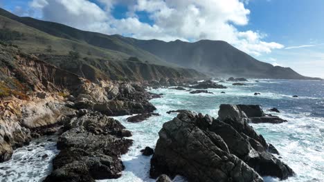 Aerial-view-of-waves-crashing-against-rocks-at-Big-Sur,-view-of-Santa-Lucia-Mountains