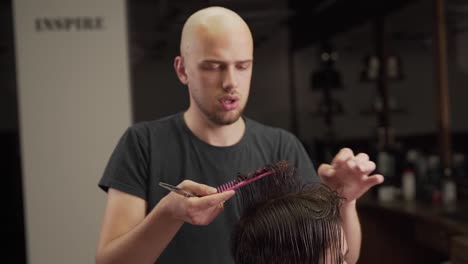 Portrait-of-a-bald-barber-performing-a-men's-haircut