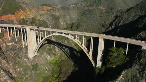 Aerial-view-of-Bixby-Bridge-as-cars-pass-over-arched-bridge-along-Highway-1-Big-Sur,-California
