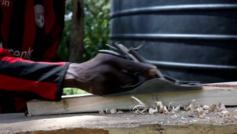 Tischler-In-Nairobi,-Kenia,-Verwendet-Einen-Handhobel,-Um-Ein-Stück-Holz-Für-Ein-Möbelprojekt-Zu-Formen-Und-Zu-Glätten