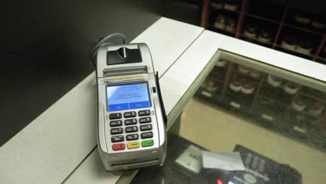 Used-Credit-Card-Scanner-On-Old-Bowling-Center-Counter-Top,-Closeup-Dolly-Out