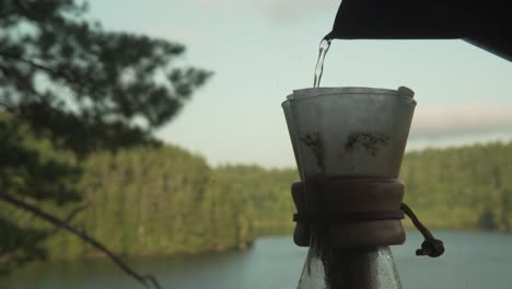 Filling-up-natural-organic-paper-coffee-filter-in-glass-Chemex-coffee-brewing-apparatus-in-Canadian-forest