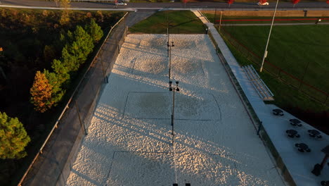 Aerial-tilt-up-reveals-outdoor-sand-volleyball-courts-during-golden-hour-light
