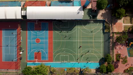 Draufsicht-Auf-Basketballplatz-Und-Fußballfelder-Mit-Spielern,-Die-Unter-Der-Sonne-Spielen