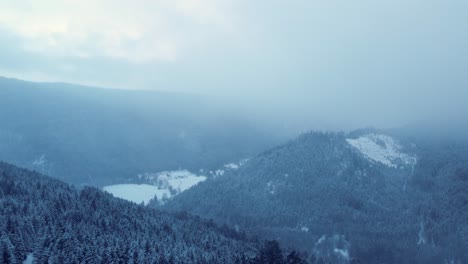 Winter-mountain-aerial-view-of-cloudy-forest-covered-snow-in-Vosges-France-4K