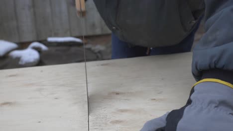 A-Man-With-Gloves-Sawing-A-Thick-Plank-Of-Wood---Close-up-shot