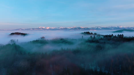 Dünne-Wolken-über-Baumwipfeln-Im-Winterwald-Bei-Sonnenuntergang-Mit-Alpenkulisse-In-Der-Nähe-Von-Lutry,-Kanton-Waadt,-Schweiz