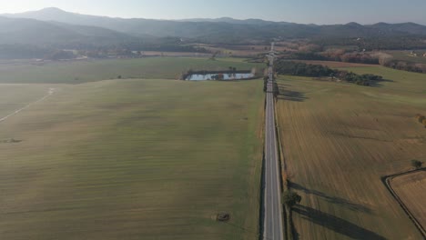 Aerial-video-of-a-newly-seeded-field-with-a-dirt-road-in-the-middle-and-mountains-in-the-background-green-Llagostera-Gerona-cultivated-field
