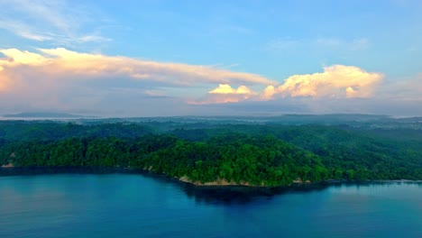 Rising-Aerial-View-of-Coiba-Island-Water-Edge-with-Dense-Jungle-Trees-and-Rock-Cliff-Shore