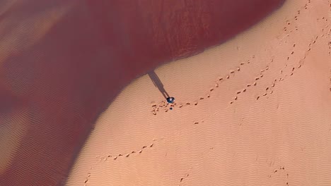 Directly-above-shot-of-man-standing-alone-in-desert-shot-with-drone,-near-Oman