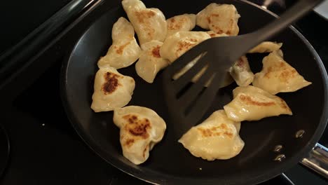 Transferring-fried-dumplings-into-the-pan,-using-a-special-spoon-for-kitchen-work