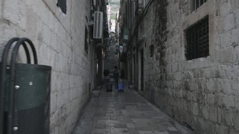 Dos-Viajeros-Caminan-Por-Un-Aliado-En-El-Casco-Antiguo,-Dubrovnik
