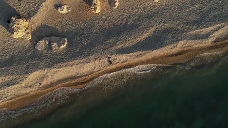 Spiral-down-drone-of-girl-lying-on-sandy-shore-on-sunny-day,-Lebanon