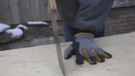 A-Man-Wearing-Gloves-Close-To-Finish-Cutting-The-Planks-Wood---Medium-shot