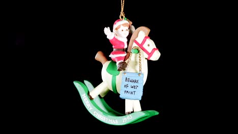 single-wooden-Christmas-ornament-of-a-boy-on-a-rocking-horse-with-black-background,-close-up