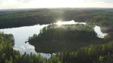 Aerial-drone-shot-of-beautiful-summer-lake-scenery-with-smoke-floating-from-sauna-in-the-woods