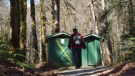 Man-in-the-forest-walking-to-outhouse-with-yellow-caution-tape-on-it