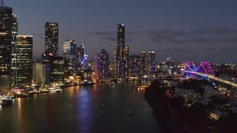 Boote-Im-Brisbane-River-Bei-Nacht-Mit-Schönem-Blick-Auf-Die-Beleuchtete-Story-Bridge-Und-Die-Wolkenkratzer-In-Brisbane,-Queensland---Luftdrohne,-Weitschuss