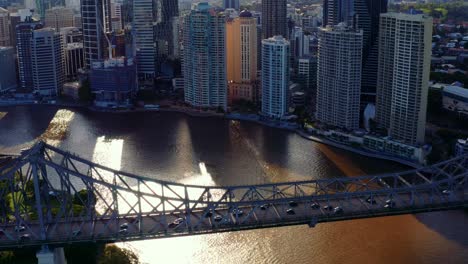 Sunlight-Shining-Through-High-Rise-Buildings-In-Brisbane-CBD-With-View-Of-Transportation-At-Story-Bridge-Across-Brisbane-River-In-Australia---pullback-drone