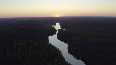 Aerial-shot-of-a-narrow-river-in-the-wilderness-by-golden-hour-after-sunset