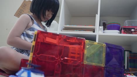 Eine-Fünfjährige-Chinesische-Indonesierin,-Die-Mit-Kunststoff-magnetblöcken-Spielt-Und-Auf-Der-Basis-Ihrer-Kreativität-Und-Initiative-Einen-Spielraum-Baut