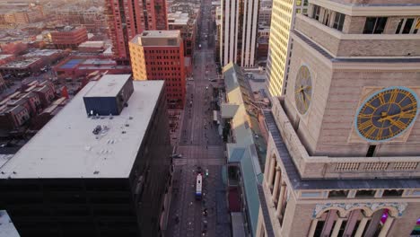 Drone-Aerial-View-Flying-By-Lannies-Clocktower-Panning-Down-To-Arapahoe-Street-Traffic-In-Downtown-Denver-Colorado-During-Sunset