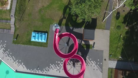 Aerial-Shot-Of-A-Girl-Riding-On-Water-Slide-To-The-Swimming-Pool