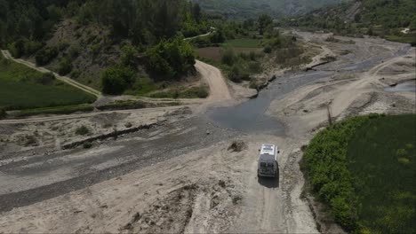 Drone-shot-of-white-van-passing-in-campspot-at-river