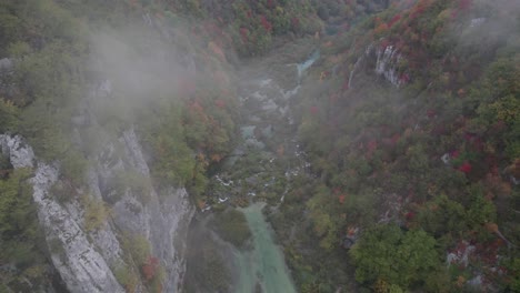 Mist-in-famous-Plitvice-river-valley-during-colorful-autumn-season,-aerial