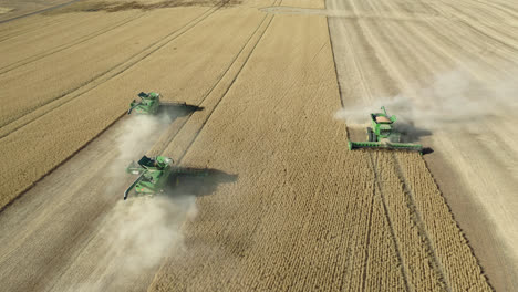 Aerial,-3-combine-harvesters-collecting-wheat-grains-from-vast-farm-field