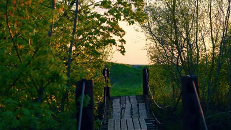 Old-Wooden-Footbridge-Leading-To-The-Road-With-Car-Driving-Slowly-At-Sunset