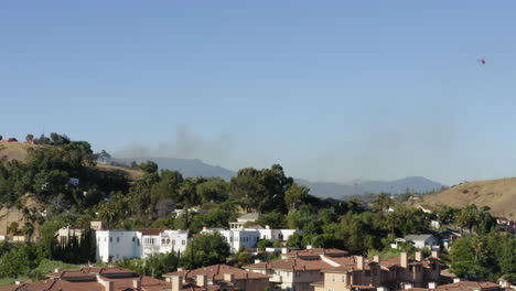 Helicopter-putting-out-brush-fire-in-Lincoln-Heights,-Los-Angeles-suburb,-aerial-view