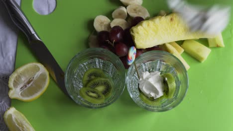 Fresh-Greek-yogurt-being-put-on-top-of-sliced-green-kiwi-with-pineapple-and-grapes
