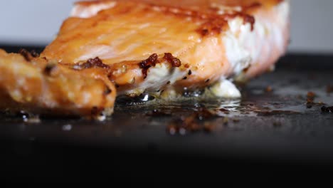 Salmon-fillet-cooking-in-fat-on-hot-pan,-low-closeup-camera-view